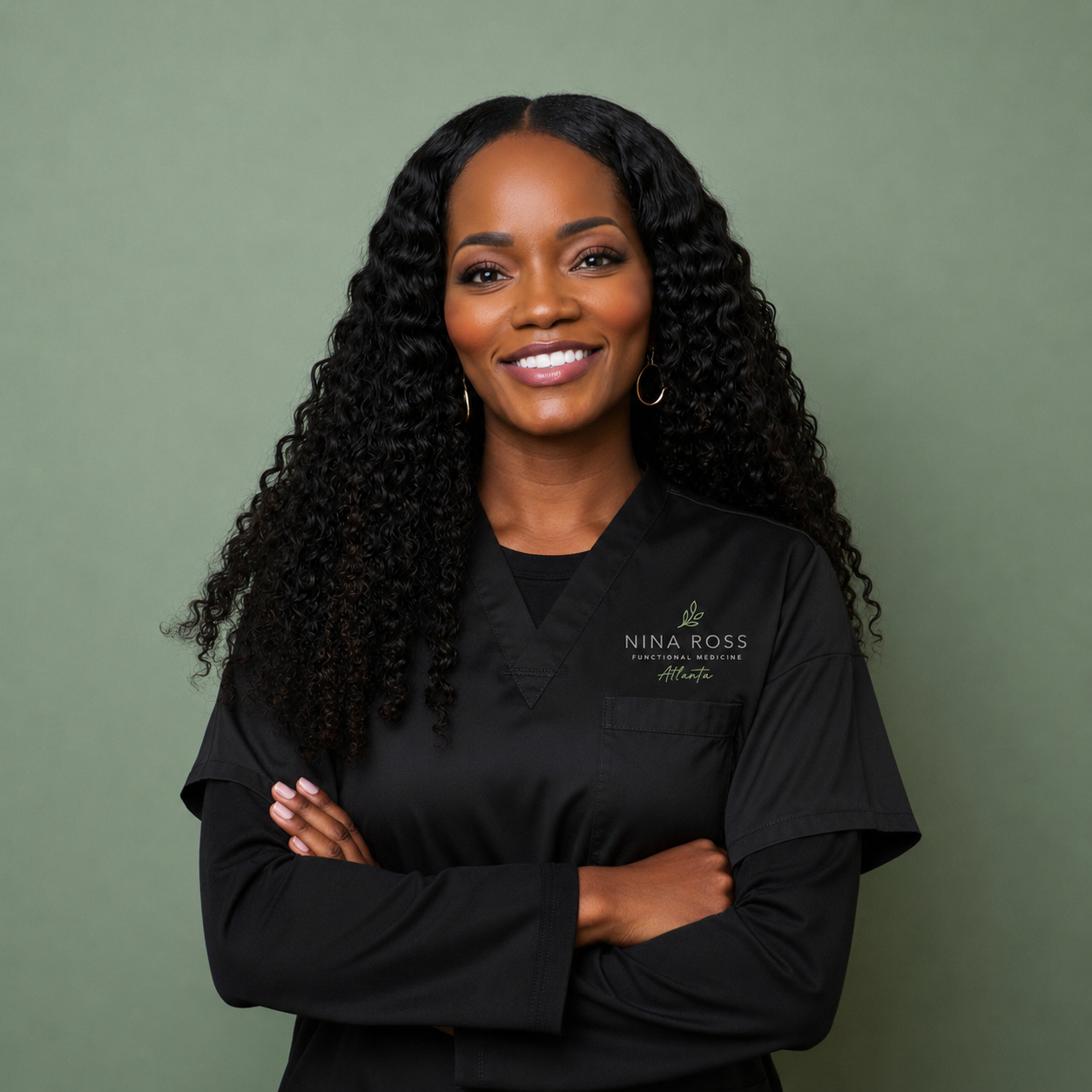 Dr. Nina Ross in black clinical scrubs with the Nina Ross Functional Medicine Atlanta logo, arms crossed, smiling against a sage green background.